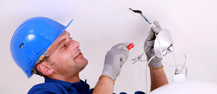 A man fixing the wires in the ceiling